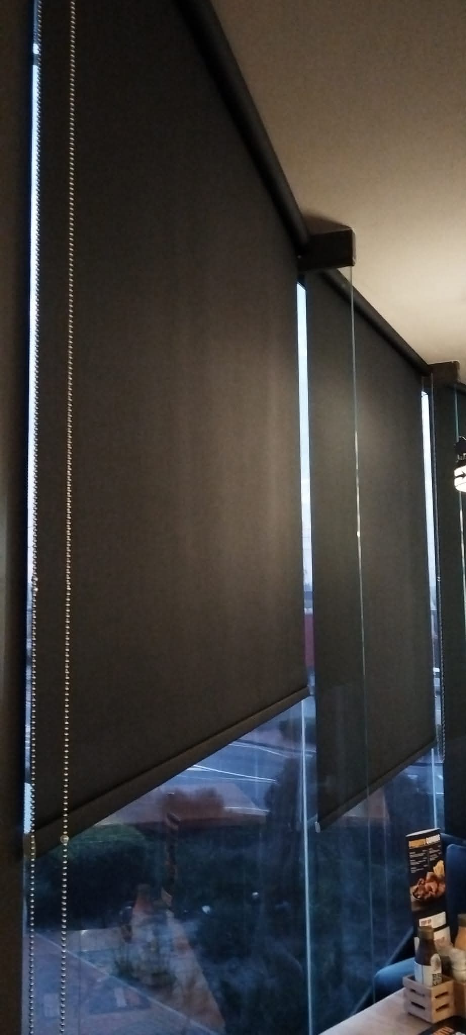 Modern grey roller blind installed in a living room window.