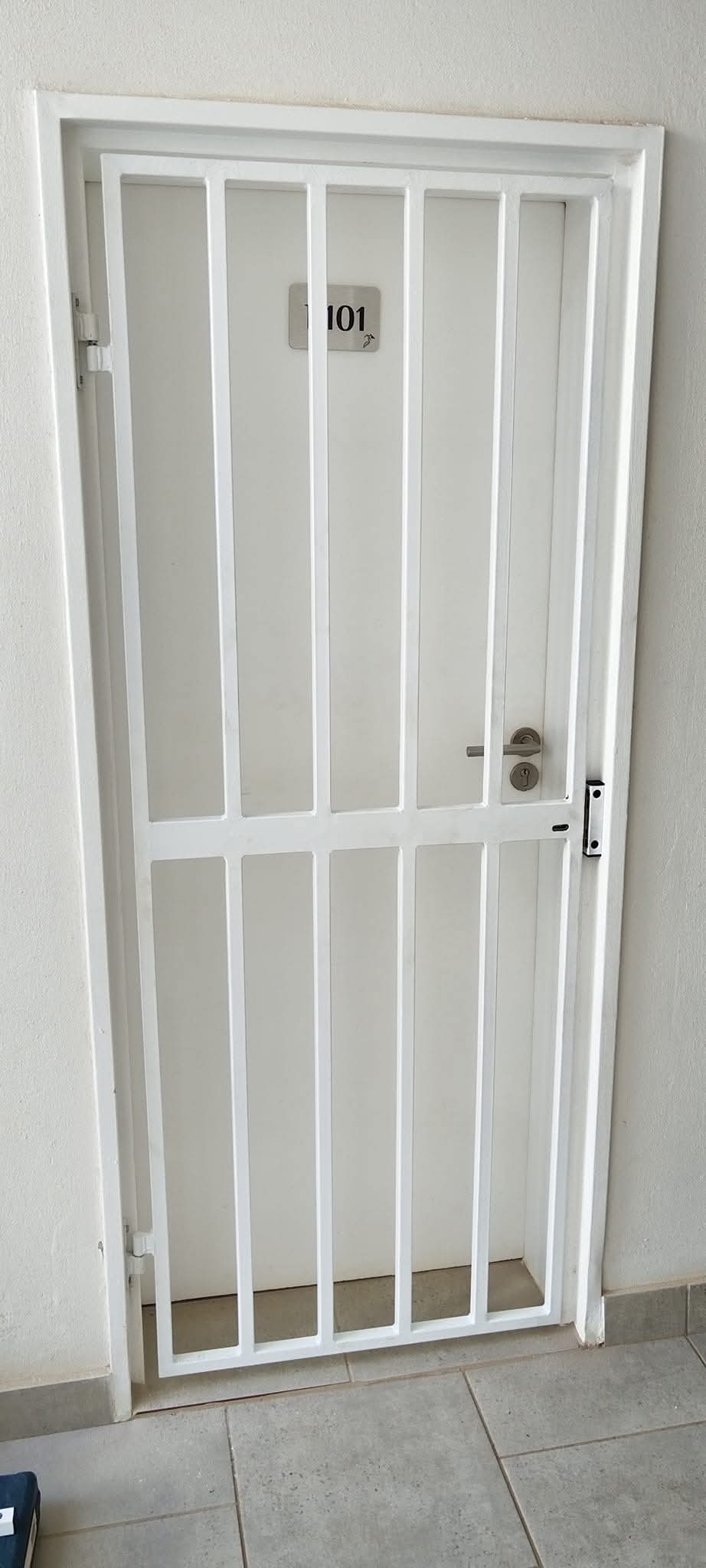A white, retractable security trellis gate securing a doorway.
